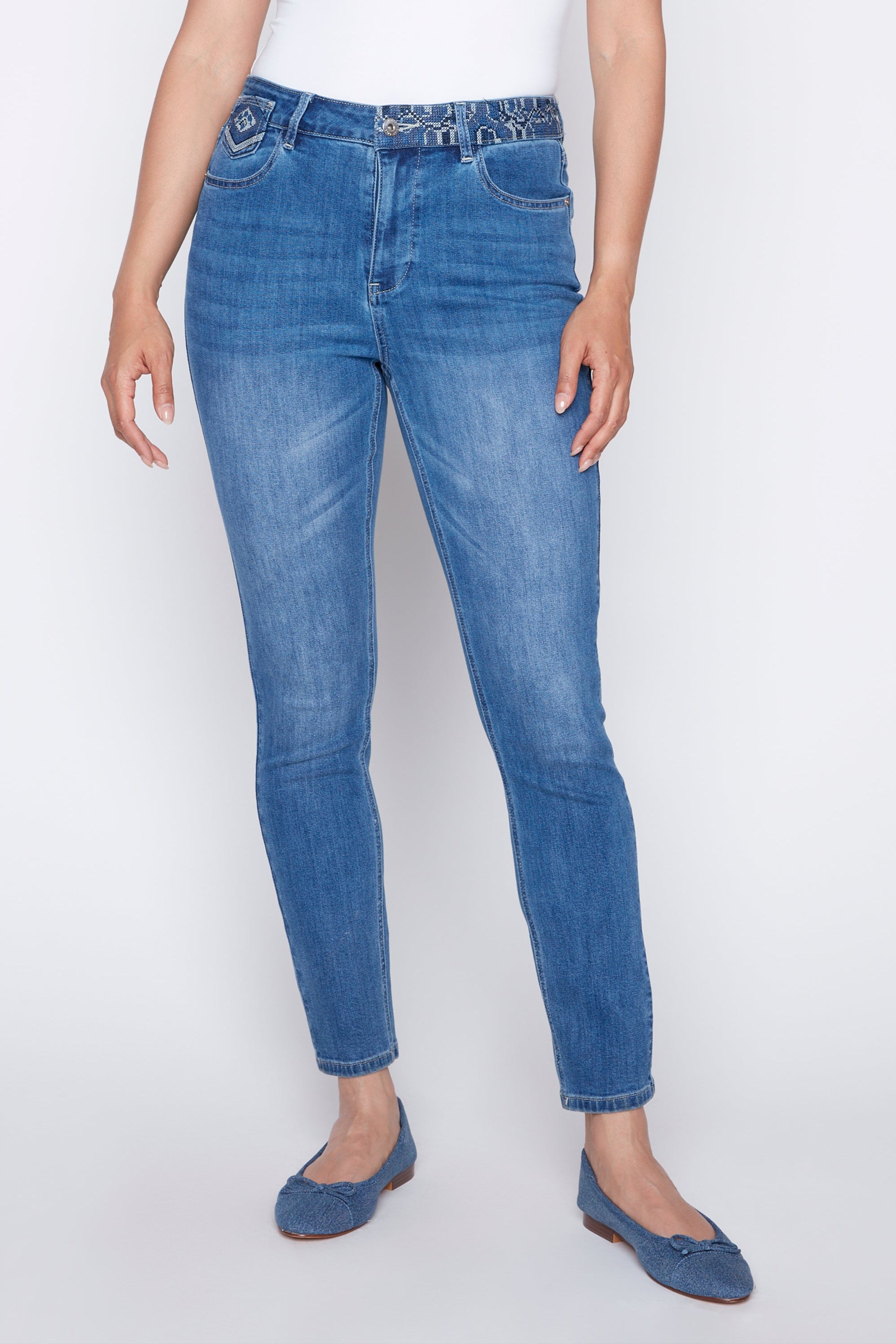 Woman wearing a white top and blue jeans on a white background