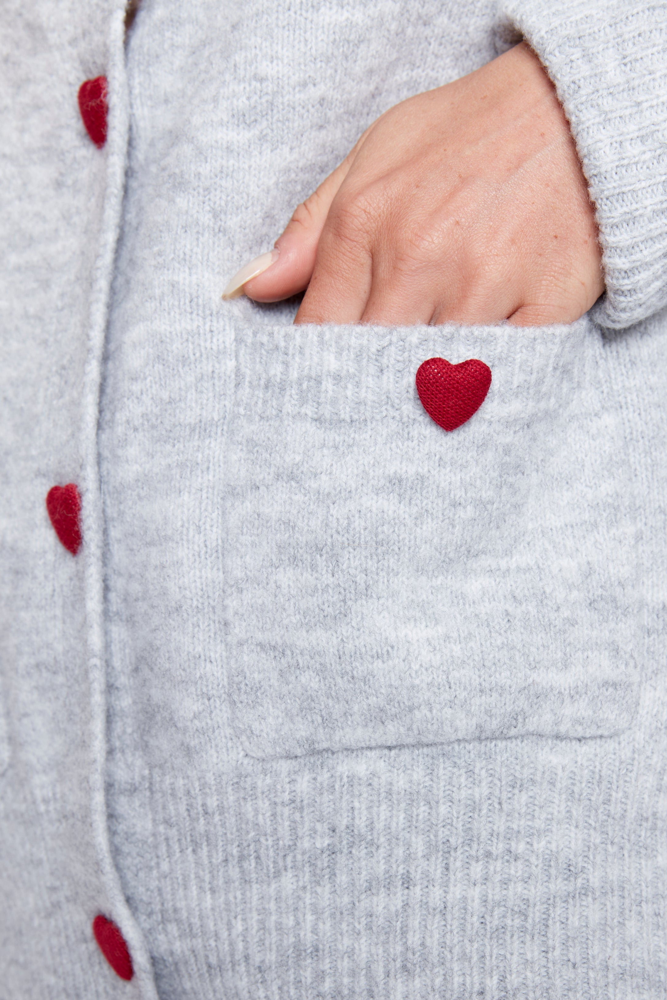 Le cardigan avec boutons à cœurs rouges